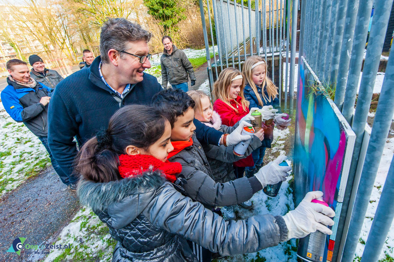(Wijk)wethouder Roy Luca verzorgt samen met buurkinderen van de graffitiworkshop de ‘finishing touch’. Samen spuiten zij het lint door.