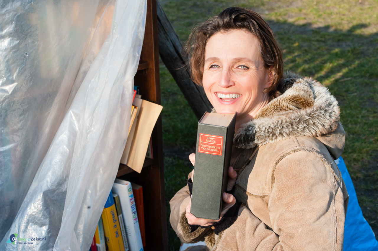 Liesbeth van Schaik zet boeken in de gemeenschappelijke boekenkast in de Allegrotuin